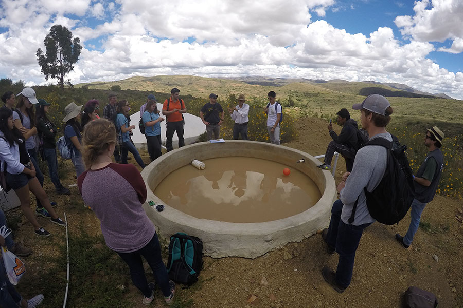 Students learn about a rainwater collector in the El Campo community from a local engineering during their Spring Break research trip to Bolivia. 