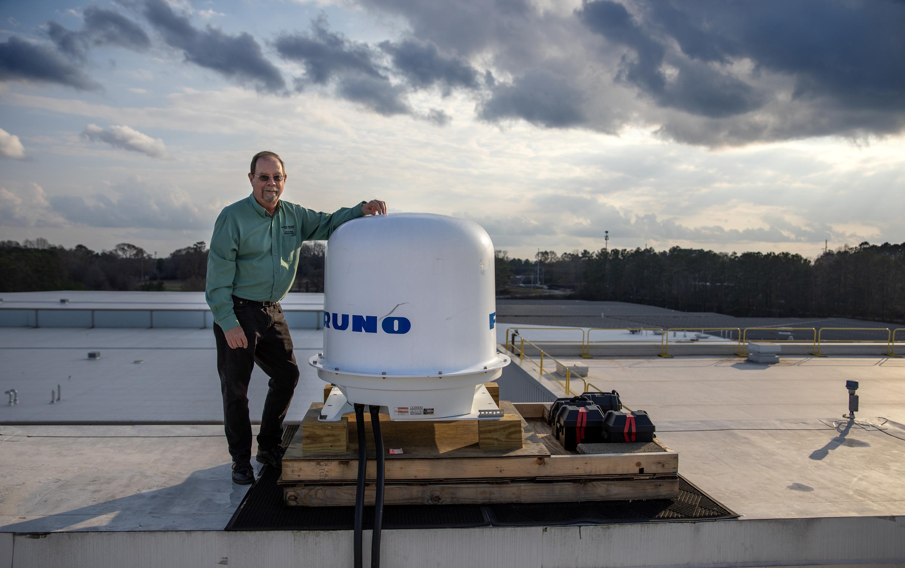 John Trostel, director of GTRI's Severe Storms Research Center, with the new weather radar atop a GTRI building. (Credit: Sean McNeil, GTRI)